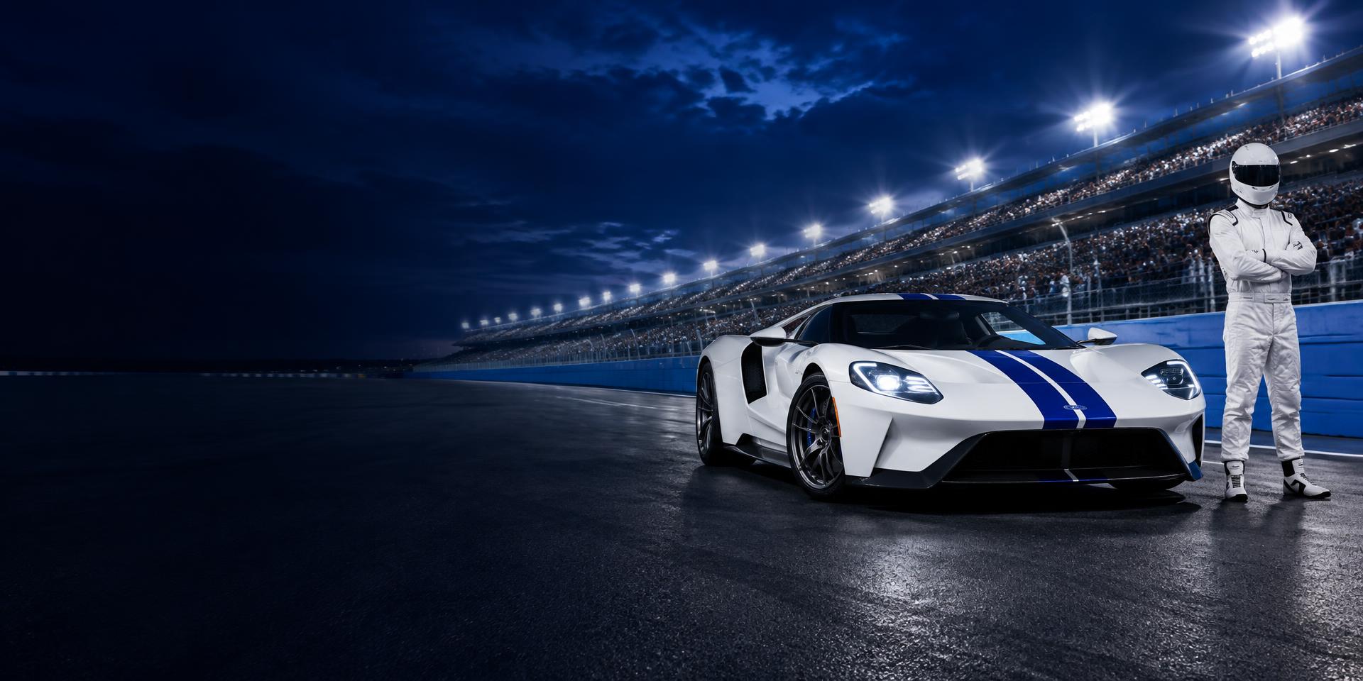 White and blue supercar and a racing driver at a floodlit speedway